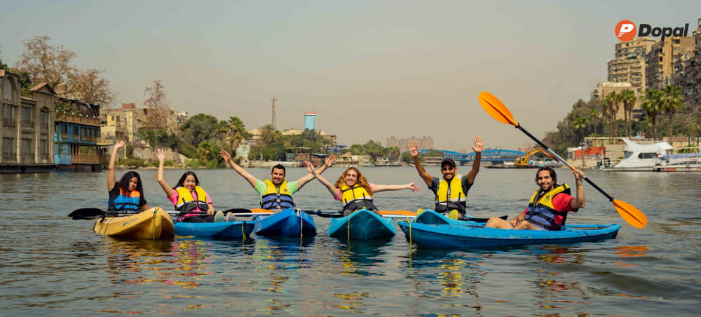 Calm Nile River view with palm trees, sandy riverbank, and Cairo buildings under a hazy morning sky
