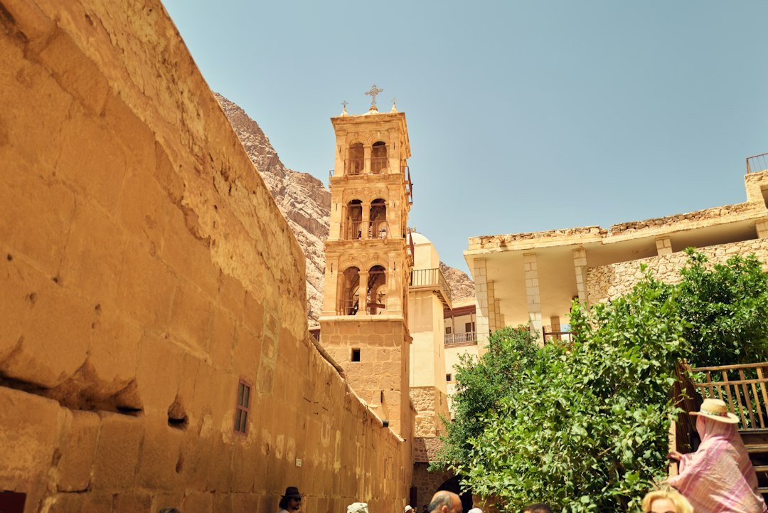 Stone bell tower with cross atop Saint Catherine's Monastery, framed by ancient walls and rocky Sinai mountains