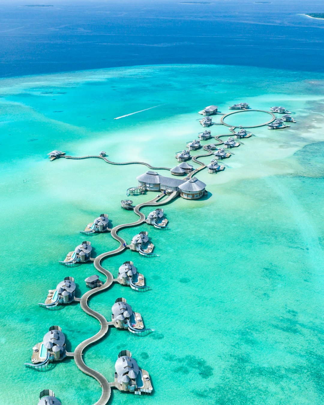 Aerial view of luxury overwater villas connected by winding jetties over turquoise Maldives lagoon