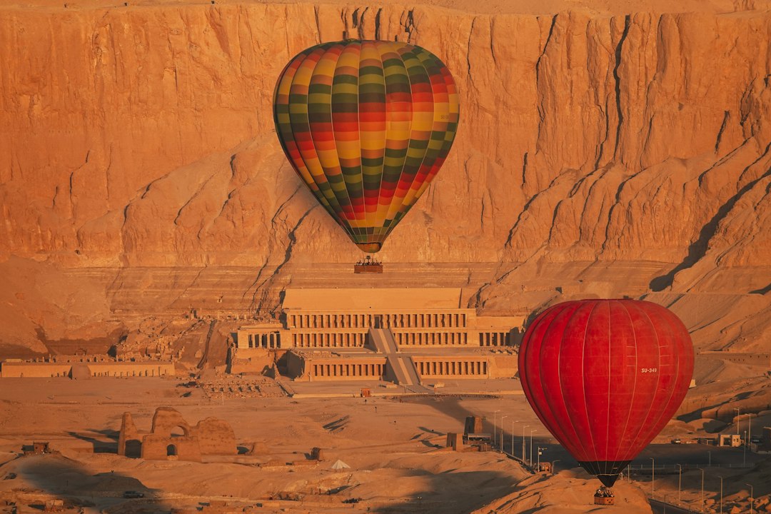 Two hot air balloons floating over the Temple of Hatshepsut at sunrise, Luxor, Egypt